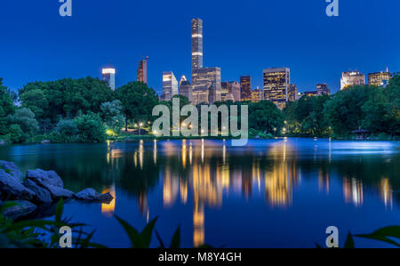 Skyline illuminée reflète dans le lac de Central Park, New York City Banque D'Images