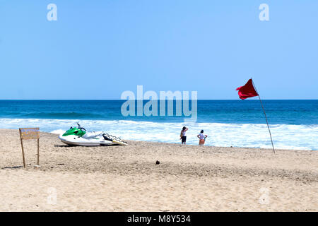 Vert et blanc Yamaha WaveRunner comme échoués sur Jules Verne quelques créature mer près de 2 femmes regardant dehors à la mer tout en drapeau rouge indique un danger pour les nageurs Banque D'Images