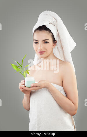 Modèle de Spa Woman holding crème cosmétique et des feuilles de bambou Banque D'Images