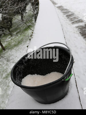 Godet noir avec du sel utilisé pour faire fondre la glace et la neige du trottoir après la chute de neige Banque D'Images