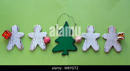 Gingerbread men découpage d'un ornement en bois d'un arbre de Noël et donner des cadeaux sur un fond de bois blanc rustique sur le dessus d'un fond vert Banque D'Images