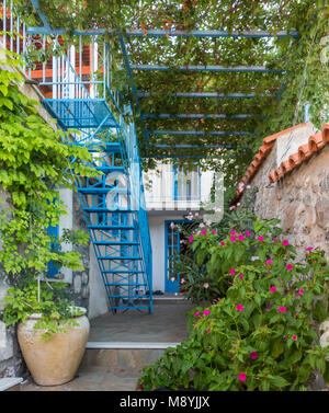 Fleurs dans un village grec jardin avec des pots de fleurs, treillis et escaliers Banque D'Images