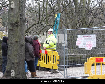 Les abattages d'arbres controversée de Sheffield. Un garde de sécurité est confronté à un obstacle extérieur manifestants autour d'un arbre pour être abattus pancartes accrochées sur obstacle Banque D'Images