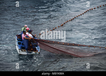 Pêcheur dans un petit bateau transportant dans leurs filets Banque D'Images