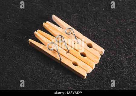 Trois colliers en bois clothespin isolé sur un fond texturé noir. Banque D'Images