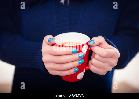 Hands holding mug à pois de boisson chaude, close-up. Banque D'Images