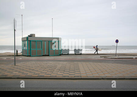 Lone surfer en maillot de bain en néoprène sur la chaussée de marche de plage vide sur un hiver froid couvert 24. La Haye, Pays-Bas Banque D'Images