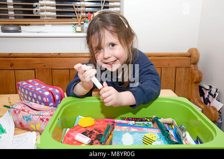 Jeune fille d'âge préscolaire s'assit à table de un stylo Banque D'Images