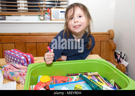 Jeune fille s'assit à table à l'aide de feutres à colorier Banque D'Images