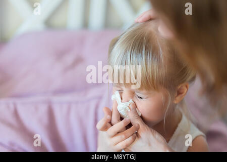 Enfant avec le nez. Aider la mère de souffler kid's nose avec mouchoir en papier. Maladie saisonnière. Banque D'Images