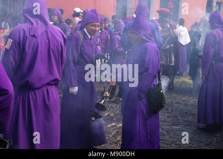 Deux jeunes hommes en robe pourpre de la fumée d'encens à la procession de San Bartolomé de Becerra dans 1a avenida, Antigua, Guatemala Banque D'Images