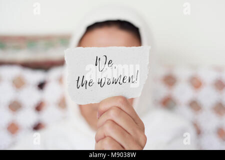Libre à l'intérieur d'une jeune femme portant un foulard blanc montrant un morceau de papier devant son visage avec le texte que nous les femmes écrit en c Banque D'Images