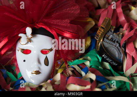 Close-up d'un masque de carnaval de Pierrot sur un arrière-plan avec une gondole vénitienne et de banderoles colorées Banque D'Images