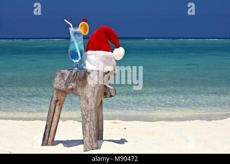 Bocal d'eau tonique est sur la plage d'origine le tableau est fait de tronc d'arbre avec Santa hat Banque D'Images