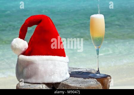 Bocal de champagne est sur la plage d'origine le tableau est fait de tronc d'arbre avec Santa hat Banque D'Images