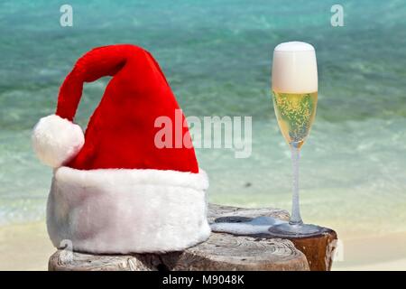 Bocal de champagne est sur la plage d'origine le tableau est fait de tronc d'arbre avec Santa hat Banque D'Images