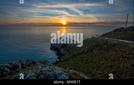 Le soleil se couche derrière le phare de South Stack à Anglesey, dans le nord du pays de Galles, tandis que les conditions glaciales de la « mini Bête de l'est » s'accrochent encore une journée avant le retour du printemps en Grande-Bretagne. Banque D'Images