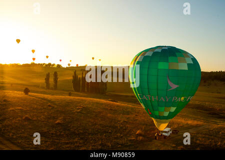 Ballon Vert prêt à décoller alors qu'un groupe de ballons s'élèvent au-dessus de l'horizon avec le lever du soleil. Participer festival de montgolfières de Canberra Banque D'Images