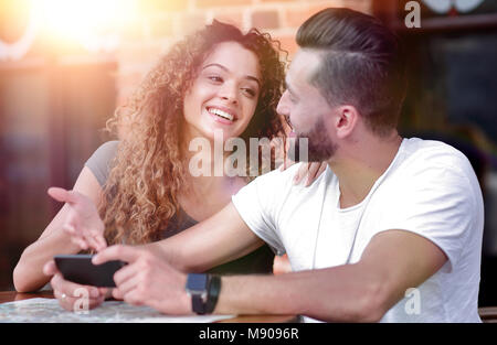 Couple heureux en utilisant un smartphone assis en terrasse Banque D'Images