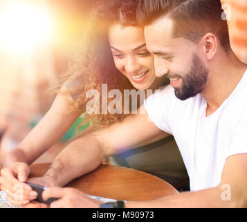 Couple heureux en utilisant un smartphone assis en terrasse Banque D'Images