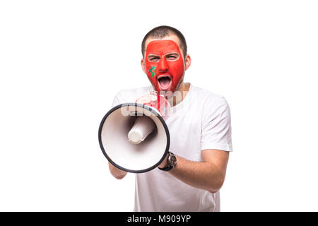 Bel homme fidèle supporter fan de l'équipe nationale du Maroc drapeau peint get happy face en criant victoire avec mégaphone fait main. Banque D'Images