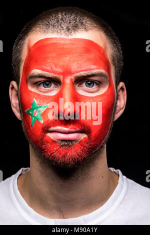 Portrait de bel homme partisan face fan de l'équipe nationale du Maroc avec drapeau peint isolé face sur fond noir. Banque D'Images