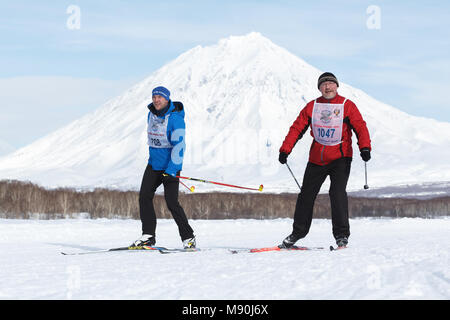 Extrême-Orient russe : - les hommes le long de la piste de ski d'hiver sur fond de Volcan Koryak. Masse de toute la compétition de ski - Piste de ski de la Russie. Banque D'Images