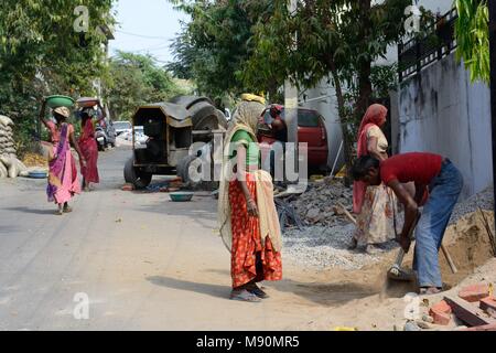 Les femmes indiennes portant des saris travaillant dans la construction la réalisation de bols de sable et de pierres sur leur tête pour faire le ciment pour la construction d'Udaipur Inde Rajashan Banque D'Images