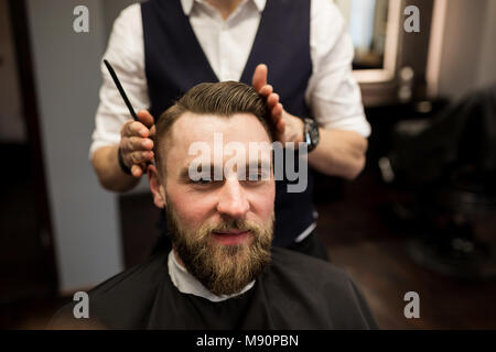 Portrait d'homme heureux faisant couper les cheveux au salon de coiffure Banque D'Images