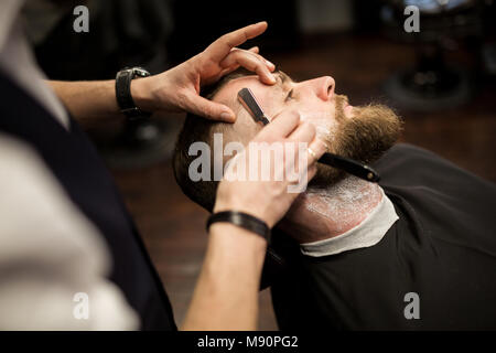 Portrait de jeune homme d'être rasé par des professionnels de coiffure Banque D'Images