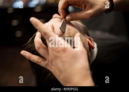 Portrait de au-dessus du client étant rasé par des professionnels de coiffure Banque D'Images