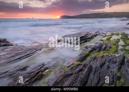 Les vagues déferlent sur les rives rocheuses de la Baie d'objets piégés au coucher du soleil, Cornwall, Angleterre. L'été (juillet) 2017. Banque D'Images