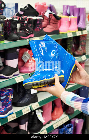 Bottes en caoutchouc pour enfants dans les mains de l'acheteur dans le magasin Banque D'Images