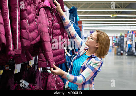 Femme choisit une veste d'hiver dans le magasin Banque D'Images