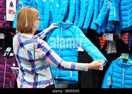 Femme choisit une veste d'hiver dans le magasin Banque D'Images