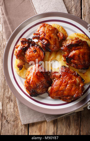 Cuisses de poulet épicées grill hawaïenne huli huli avec gros plan d'ananas sur une assiette. Haut Vertical Vue de dessus Banque D'Images