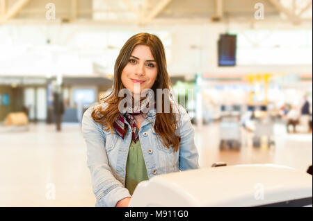 Jeune femme avec sac chariot en utilisant l'auto check-in à l'aéroport. Banque D'Images