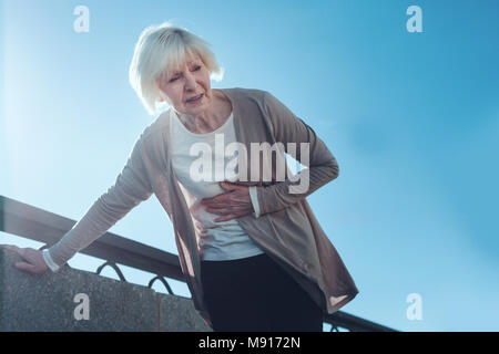 Peur senior woman having attaque cardiaque à l'extérieur Banque D'Images