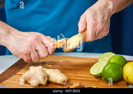 Man peeling ginger sur une planche en bois Banque D'Images