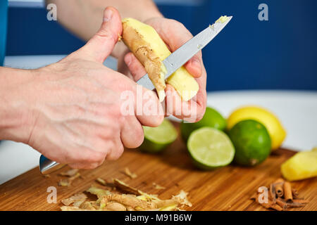 Man peeling ginger sur une planche en bois Banque D'Images