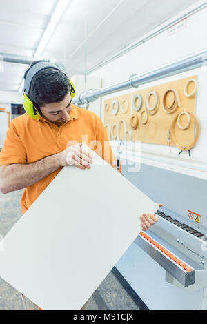 Carpenter en usine de meubles travaillant sur machine à bois Banque D'Images