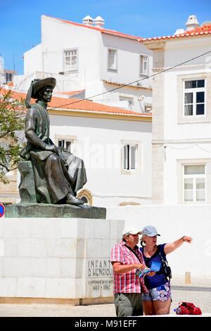 Un couple en regardant une carte devant la statue de Infante Dom Henrique (Prince Henry) sur la place de la ville avec les bâtiments de la ville à l'arrière, Lagos, Alg Banque D'Images