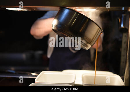 Verser la sauce dans une casserole dans un plat. Banque D'Images