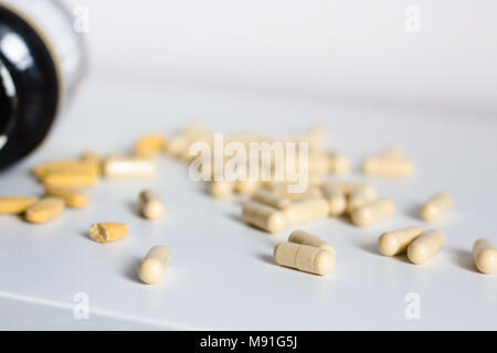 Comprimés capsules sur fond blanc être renversé au large de la bouteille sur le tableau blanc. Complément alimentaire, médical, pharmacie, santé, maladie concept Banque D'Images