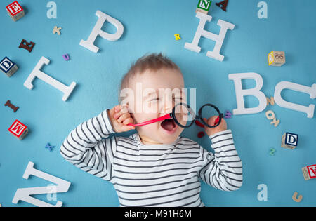 Un an enfant couché avec des lunettes et des lettres Banque D'Images