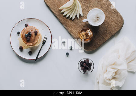 Vue de dessus de crêpes aux fruits rouges sains savoureux et tasse de cappuccino sur gris Banque D'Images