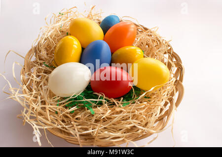 Décorations de Pâques. Oeufs colorés sur la paille dans le panier en osier. Banque D'Images