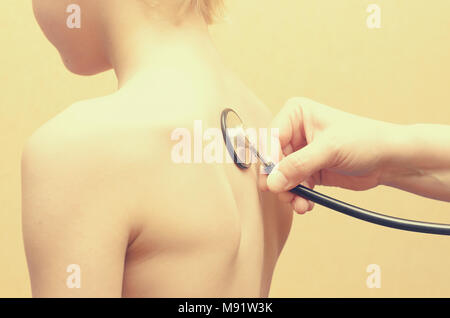 Une femme pédiatre écoute avec un stéthoscope pour le dos du garçon. Banque D'Images