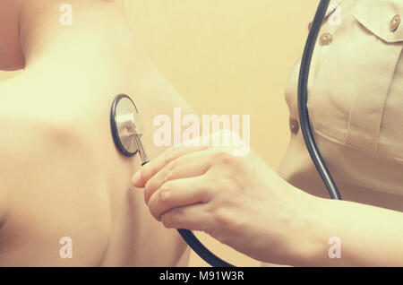 Une femme pédiatre écoute avec un stéthoscope pour le dos du garçon. Banque D'Images