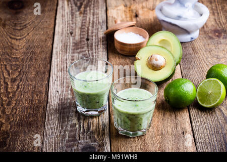 Cyril Lignac smoothie légumes vert style dans les verres avec des ingrédients de l'avocat et lime sur table en bois rustique, salé boisson laitière saine avec org Banque D'Images